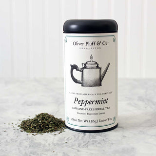 black tea tin with pile of loose leaf tea beside it on marble countertop