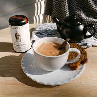 a brewed masala chai latte in white cup on wood tabletop