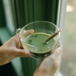brewed matcha tea in glass up in front of window frame