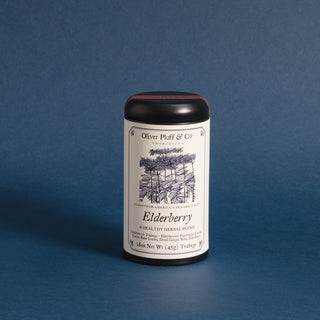 A matte black tea tin labeled 'Elderberry' by Oliver Pluff & Co. containing 20 pyramid style teabags.