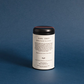round tea tin with black lid. it has a white label on a blue background. 