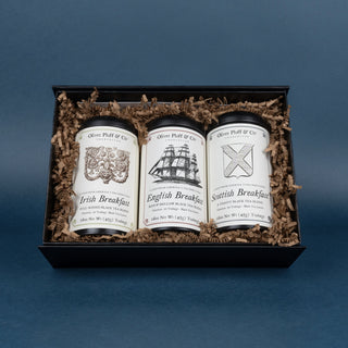 three tins in black gift box surrounded by crinkle paper