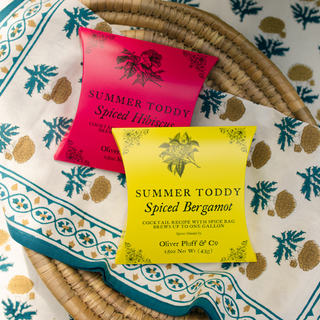 Two packets of 'Summer Toddy' spiced beverages on a decorative fabric background.