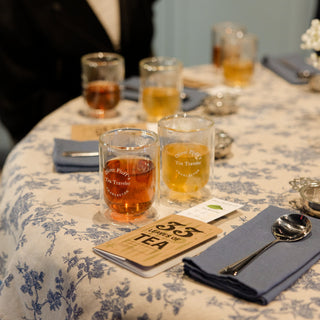 Table setting with tea glasses and coasters on a floral tablecloth